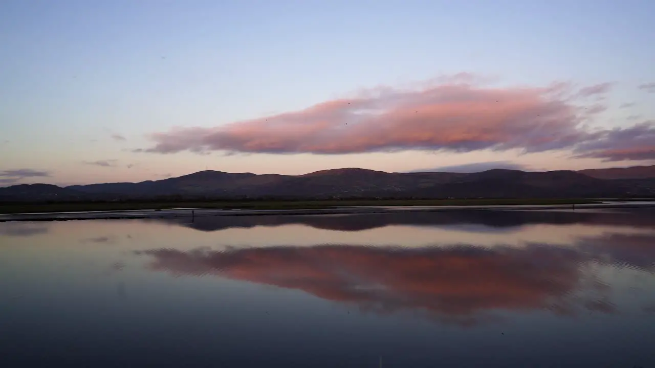 The perfect view at dusk of the water the mountains in the background and the orange sky reflecting