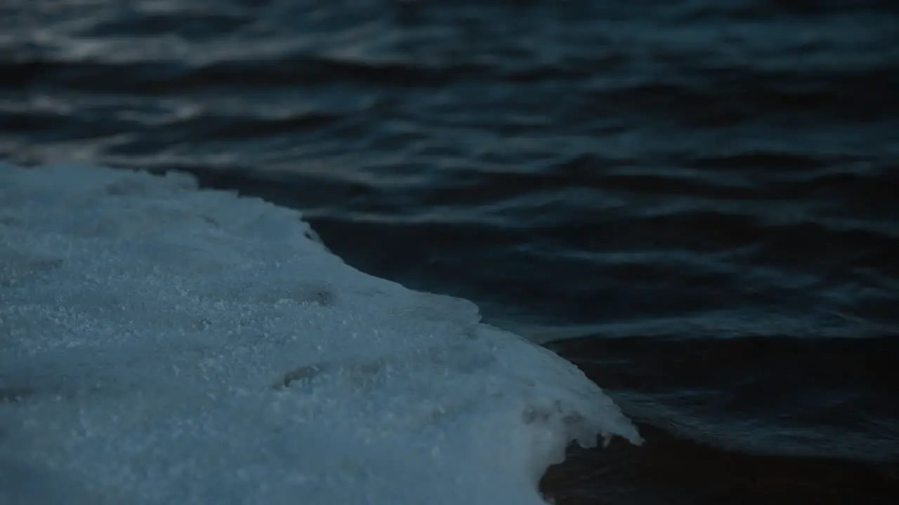 Close-up of dark rippling water on Twin Lake Colorado on a cloudy day with snow-covered shores