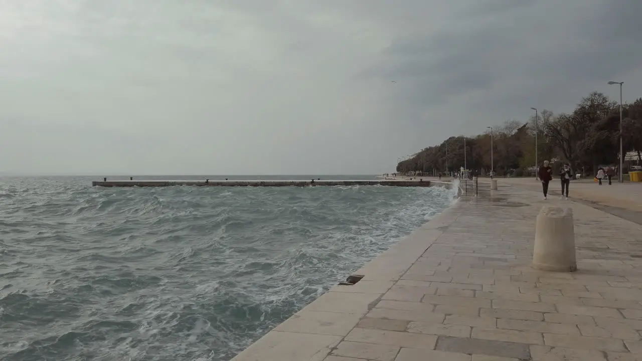 Stormy sea waves crash into the promenade