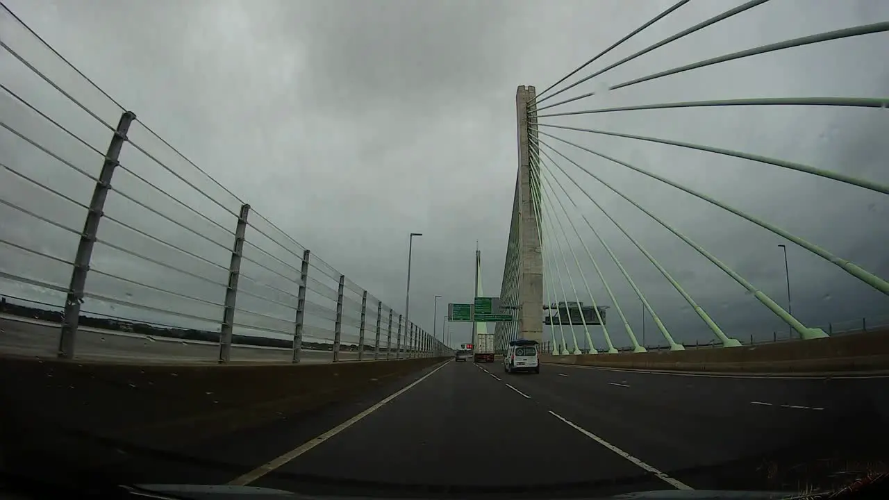 POV dash cam driving across Mersey gateway bridge in cloudy overcast morning traffic