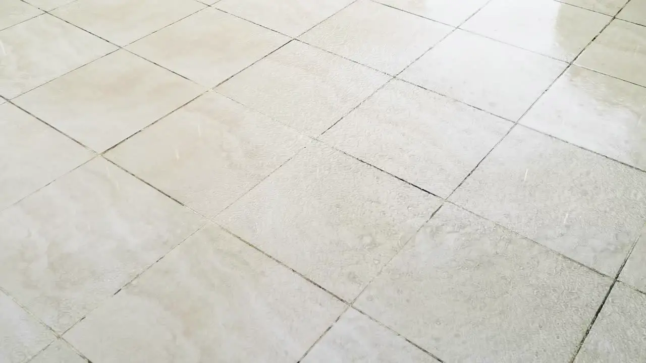 Tiled Flooring Outside with Rainwater Falling Forming a Puddle and Reflection