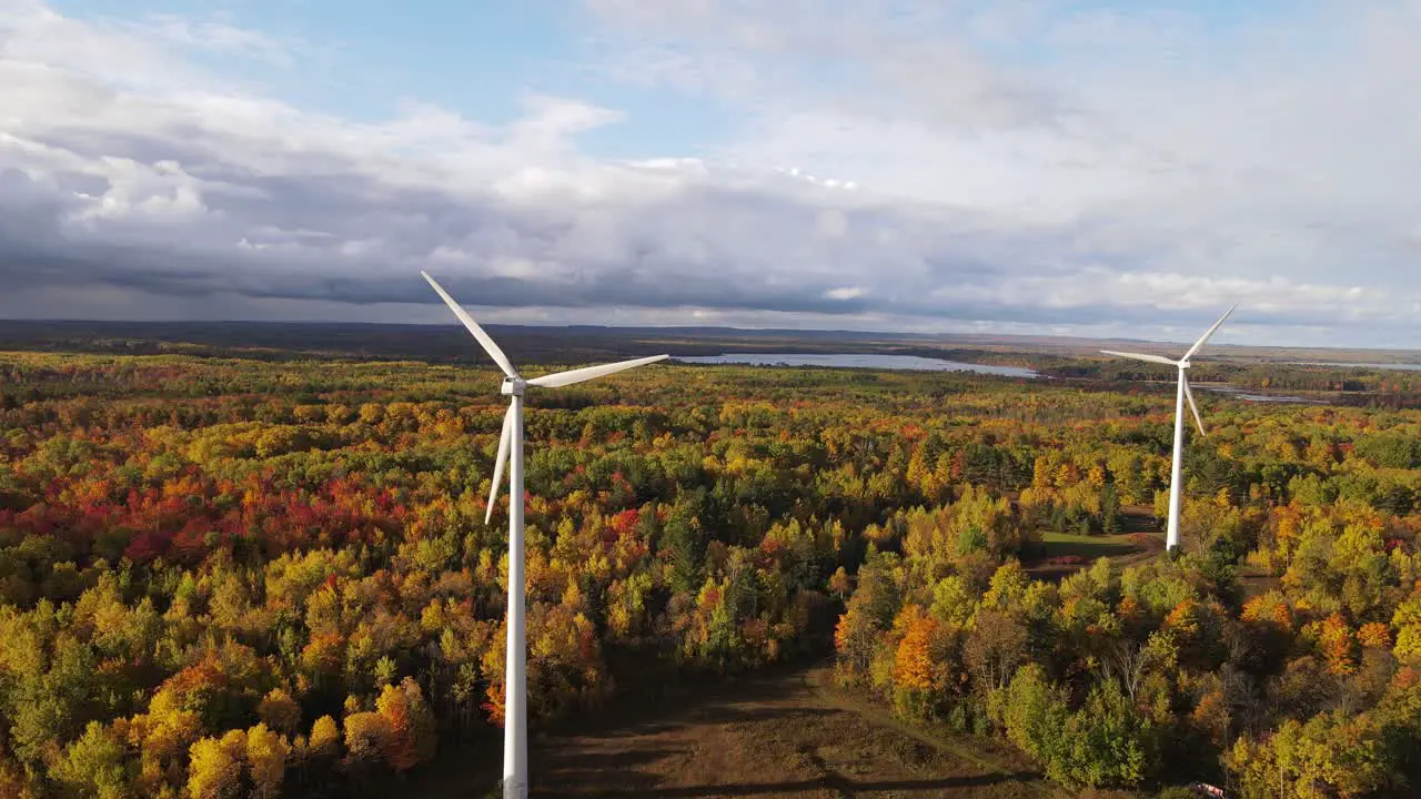 Stormy clouds coming over wind turbines and autumn colored forest aerial view