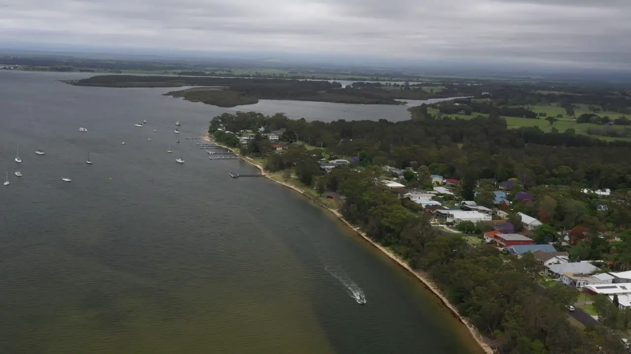 Aerial drone shot tracking a boat moving down the Shoalhaven river on a stormy day in South coast NSW Australia