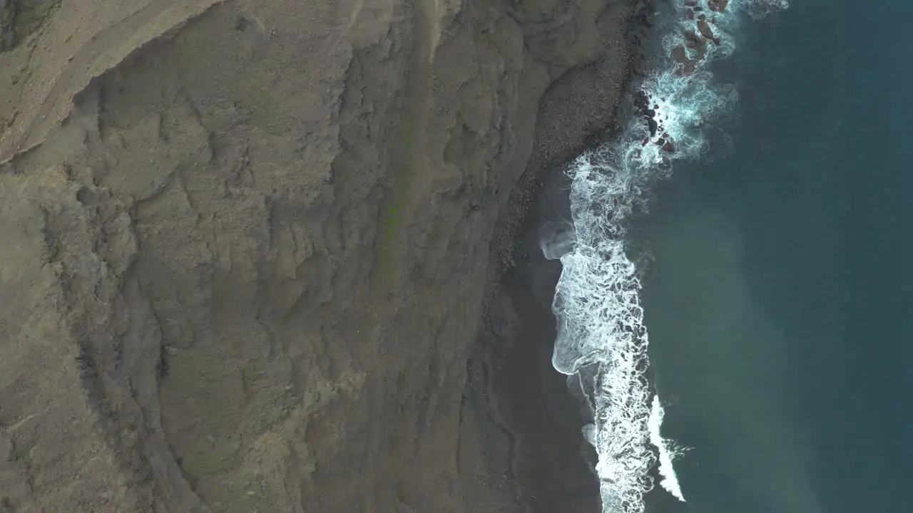 Drone top down shot of waves bounce on rocks at the coast