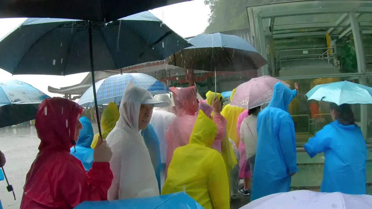 Massive tourist crowds waiting in torrential monsoon rain for public transport mini buses at the foot of Tianmen Mountain the Zhangjiajie National Park Hunan Province