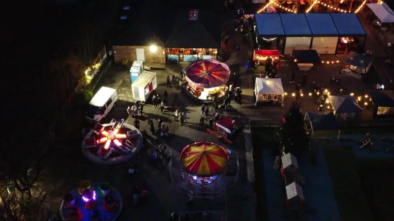 Illuminated Christmas fairground attraction in neighbourhood car park at night aerial view