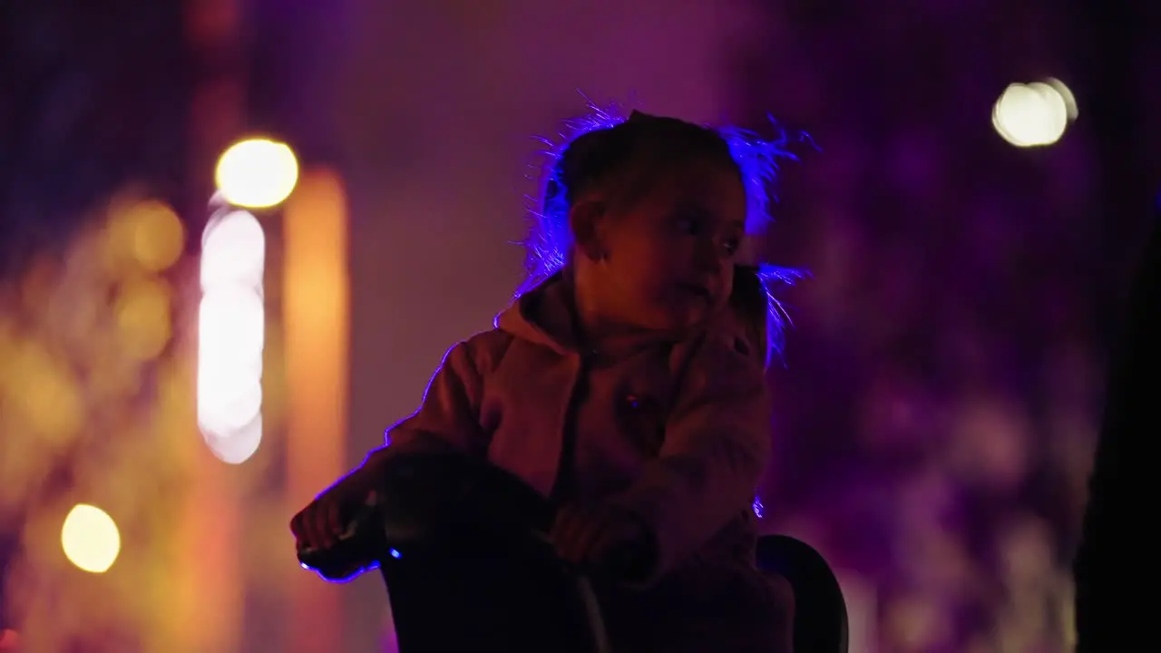 Night shot focusing on a little girl timidly riding in amusement park ride