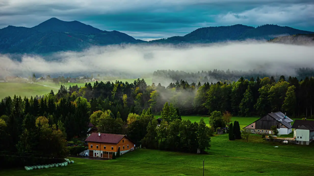 Cloudscape over a farm in Austria with low-lying fog in the valley time lapse