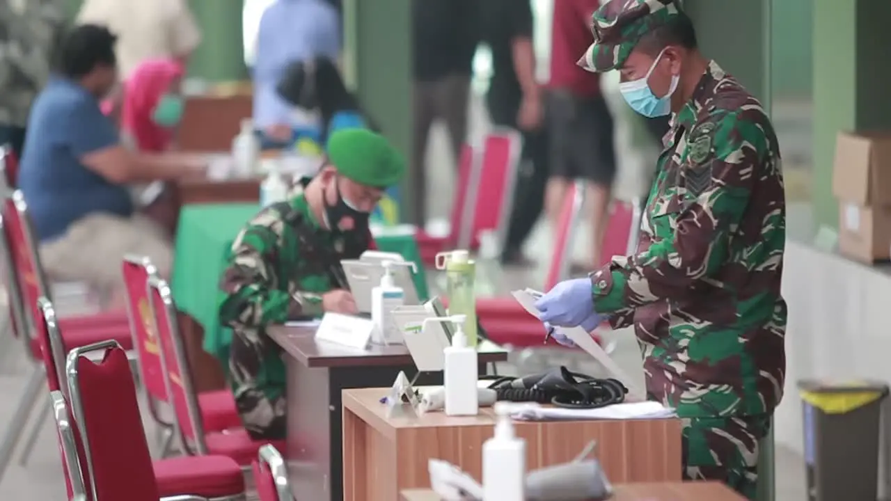 Two Indonesian National Army doctors are writing or registering patients at the registration desk in front of the hospital