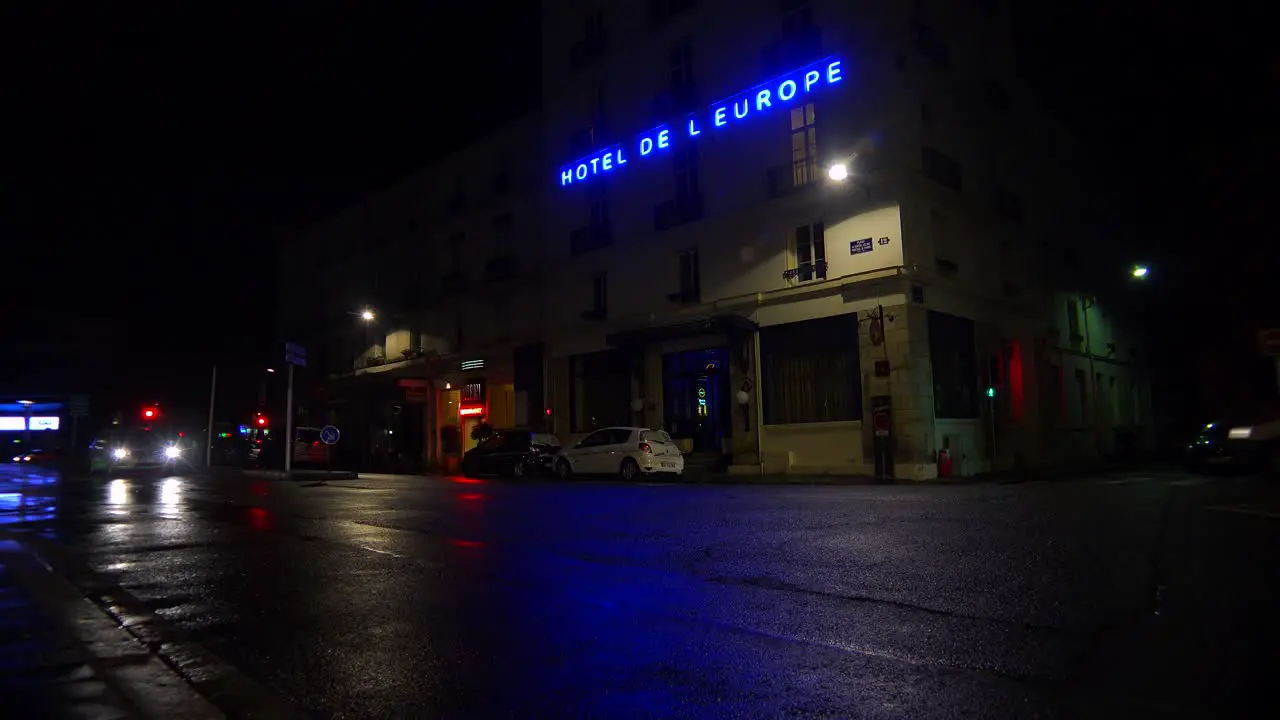 A hotel sign is reflected in rainy streets of Paris or France with a light on upstairs 2