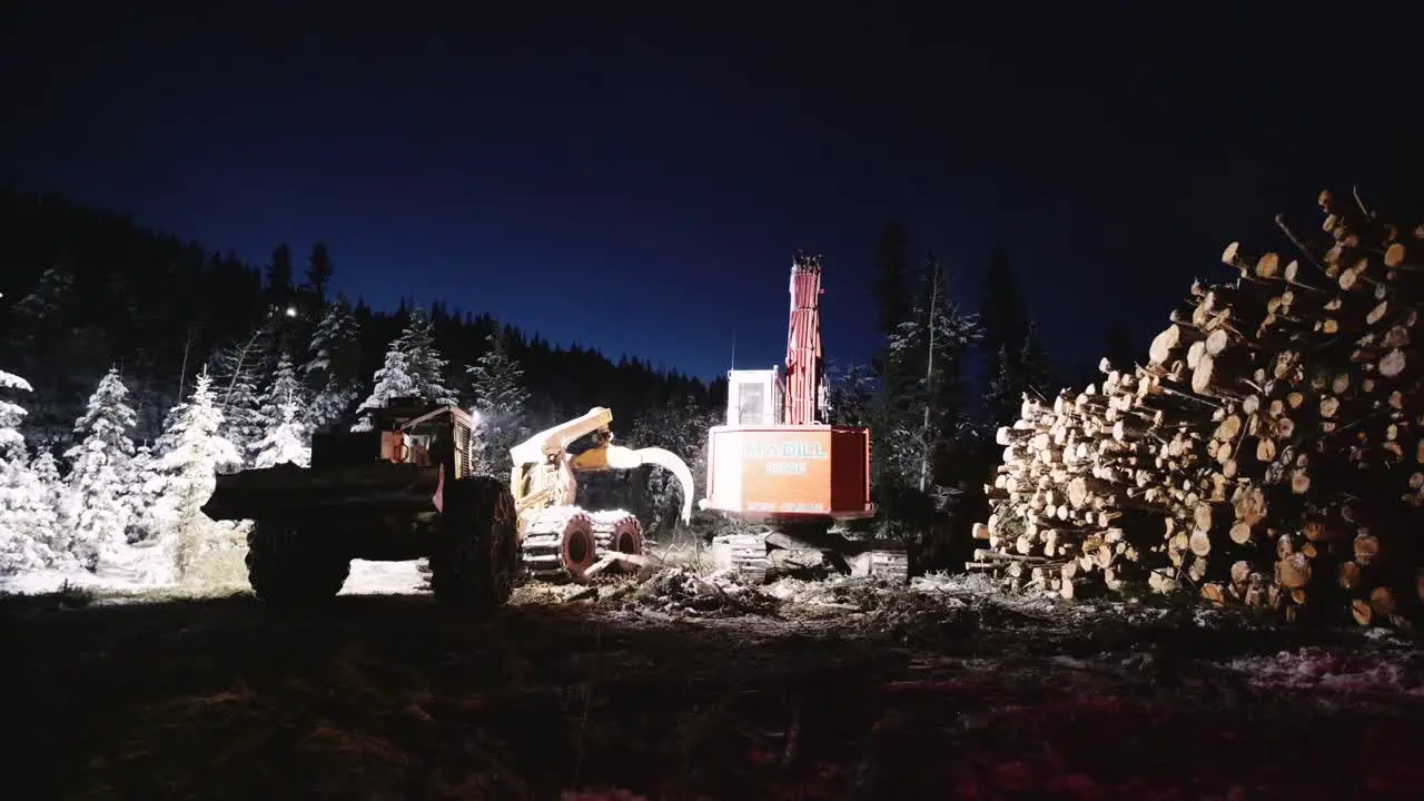 Night time industrial wood logging operation machinery moving around