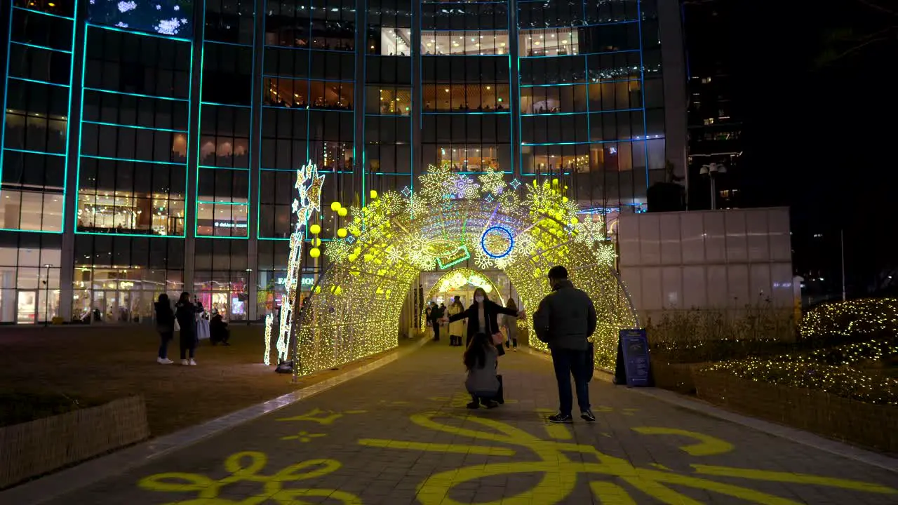 People enjoying the holiday decorations and sparkling lights at the Lotte World Tower in Seoul Korea at night wearing face masks 2021