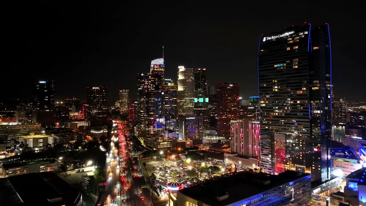 Establishing rising aerial over Los Angeles skyline of downtown at night traffic on freeway