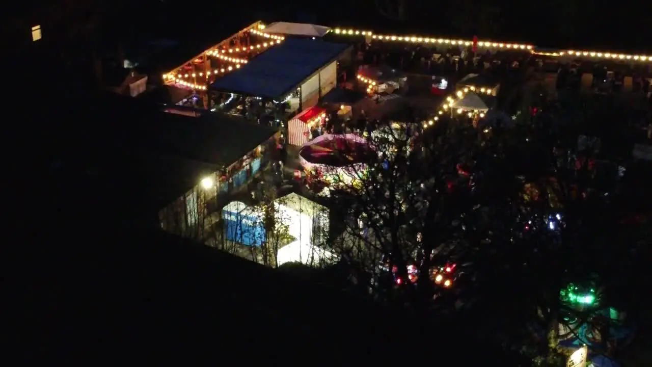 Illuminated Christmas fairground festival in neighbourhood car park at nighttime aerial view