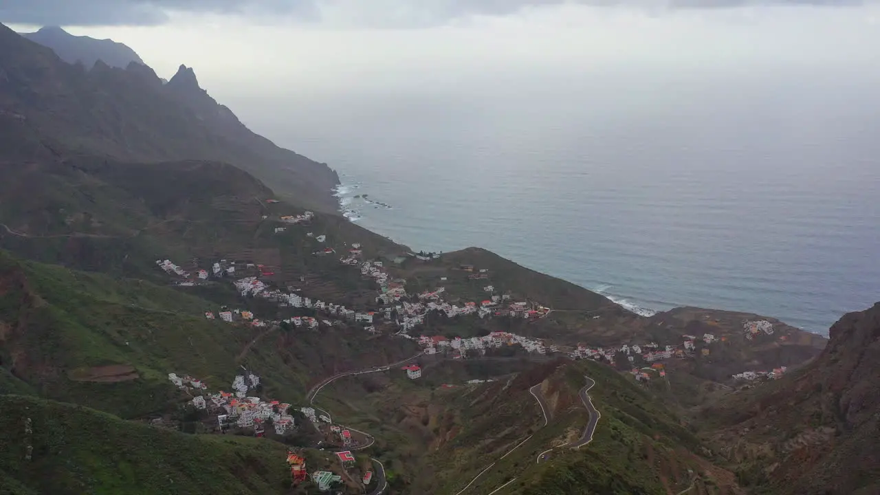 A small mountain village on the atlantic coast of the Tenerife island with the sharp distant mountain peaks hidden in stormy clouds