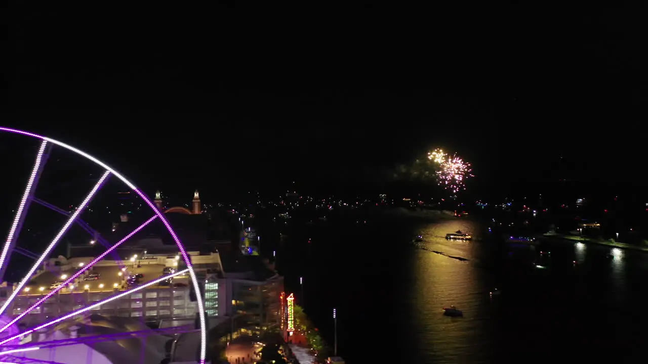 Aerial tracking shot of the illuminated Centennial Wheel revealing fireworks on Lake Michigan night in Chicago USA