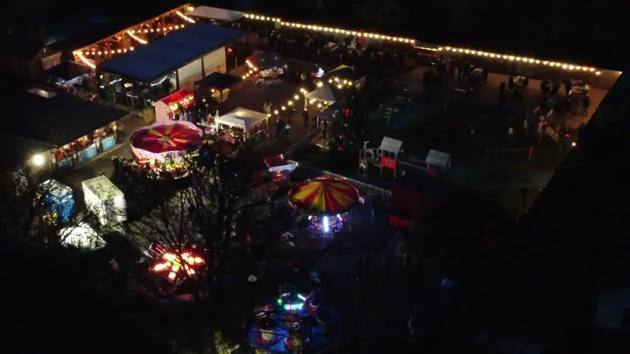 Illuminated Christmas funfair in neighbourhood car park at night aerial view