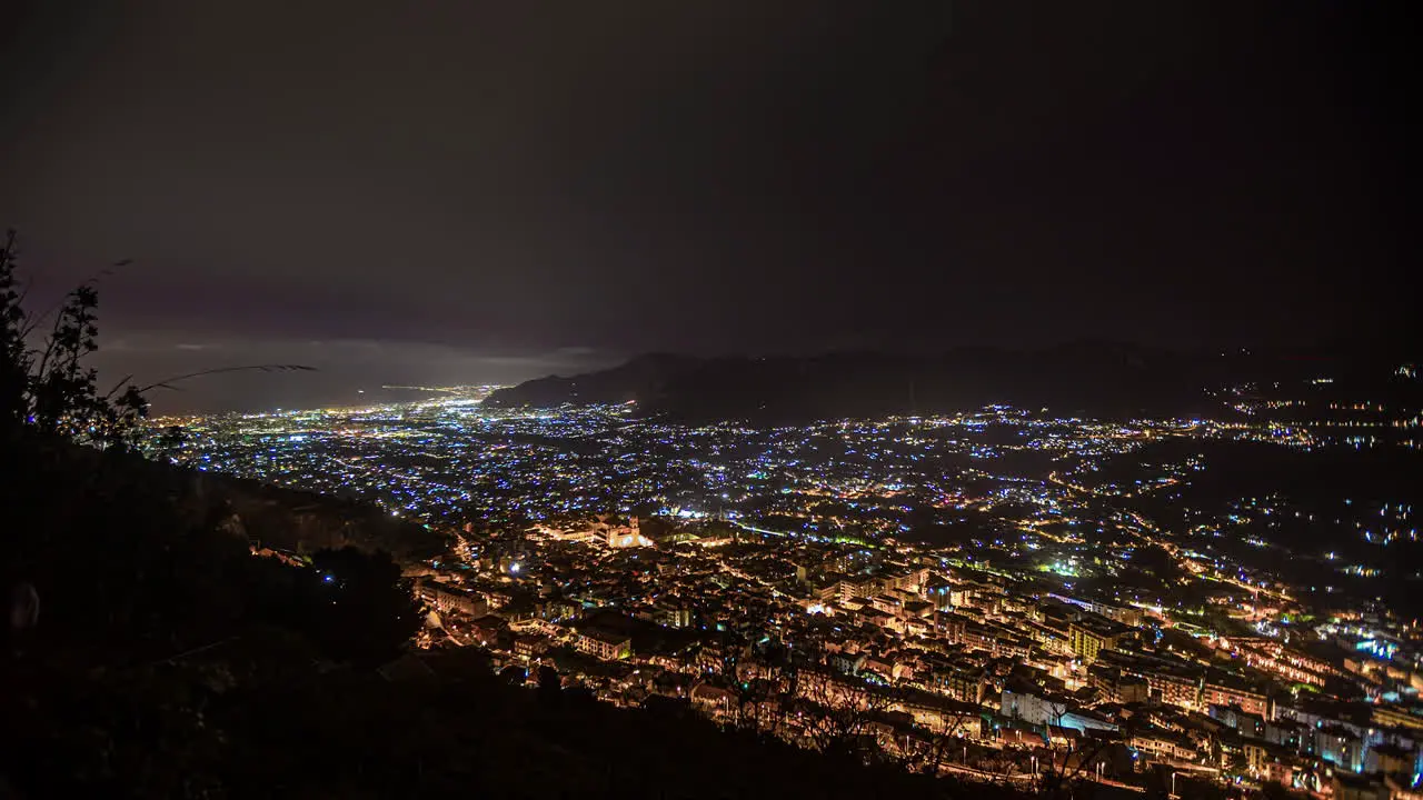 Looking over the city of Palermo Sicily at nighttime time lapse clouds coming in from the sea