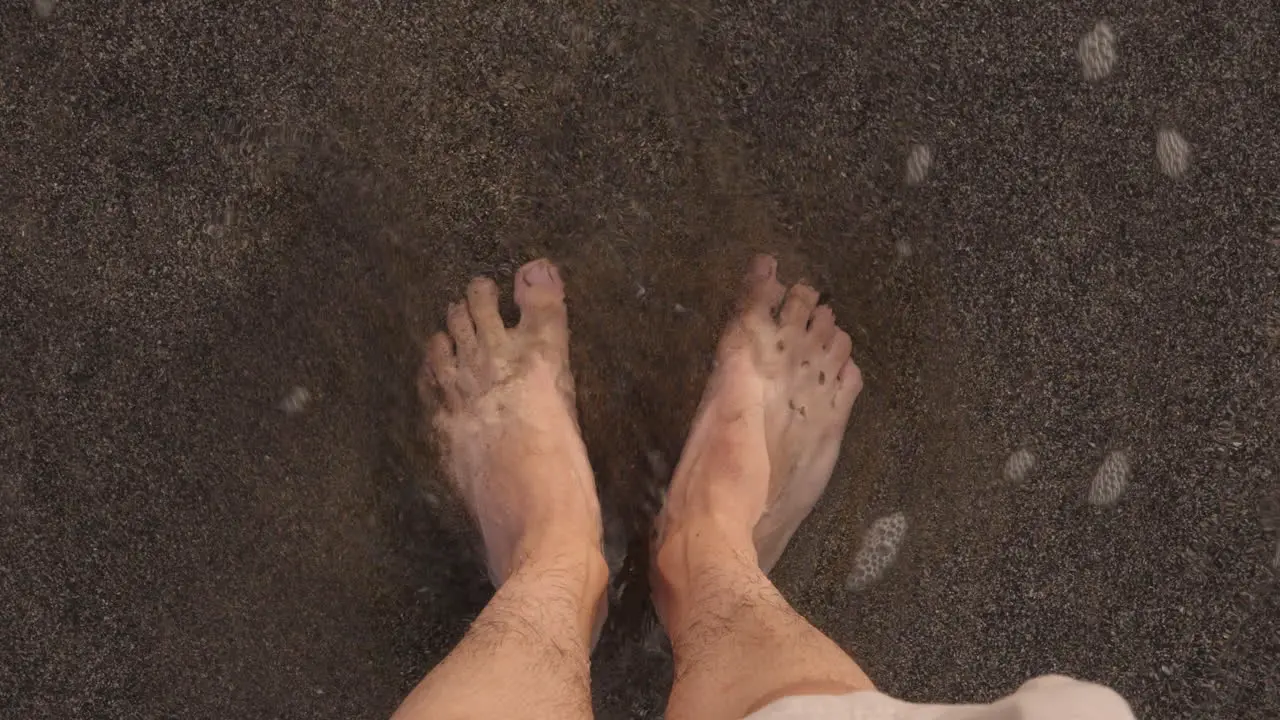 Slowmotion pov man feet foot hit by beach waves water sea sand