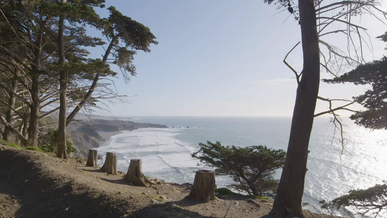 Stationary shot of cliffside hanging over the pacific ocean with waves crashing in the background located in Big Sur California