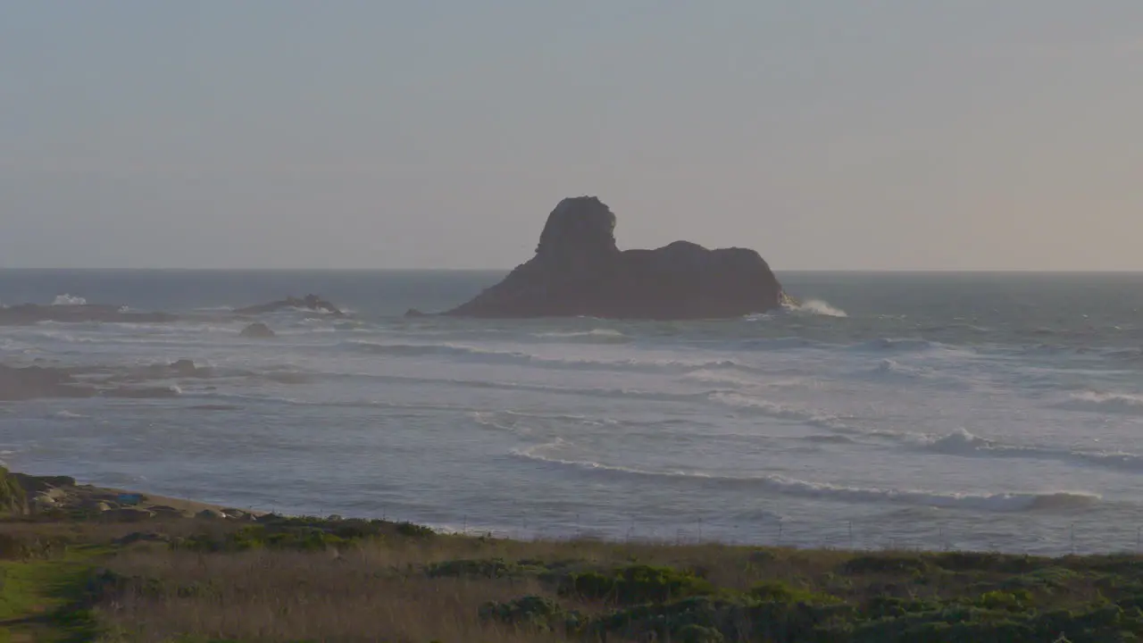 Time lapse of a huge bolder near the shore on the Pacific coast with fast moving waves crashing around it