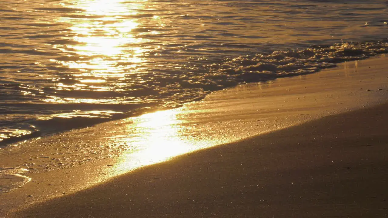 Ocean waves on golden sandy beach at sunrise mediterranean coast of Spain