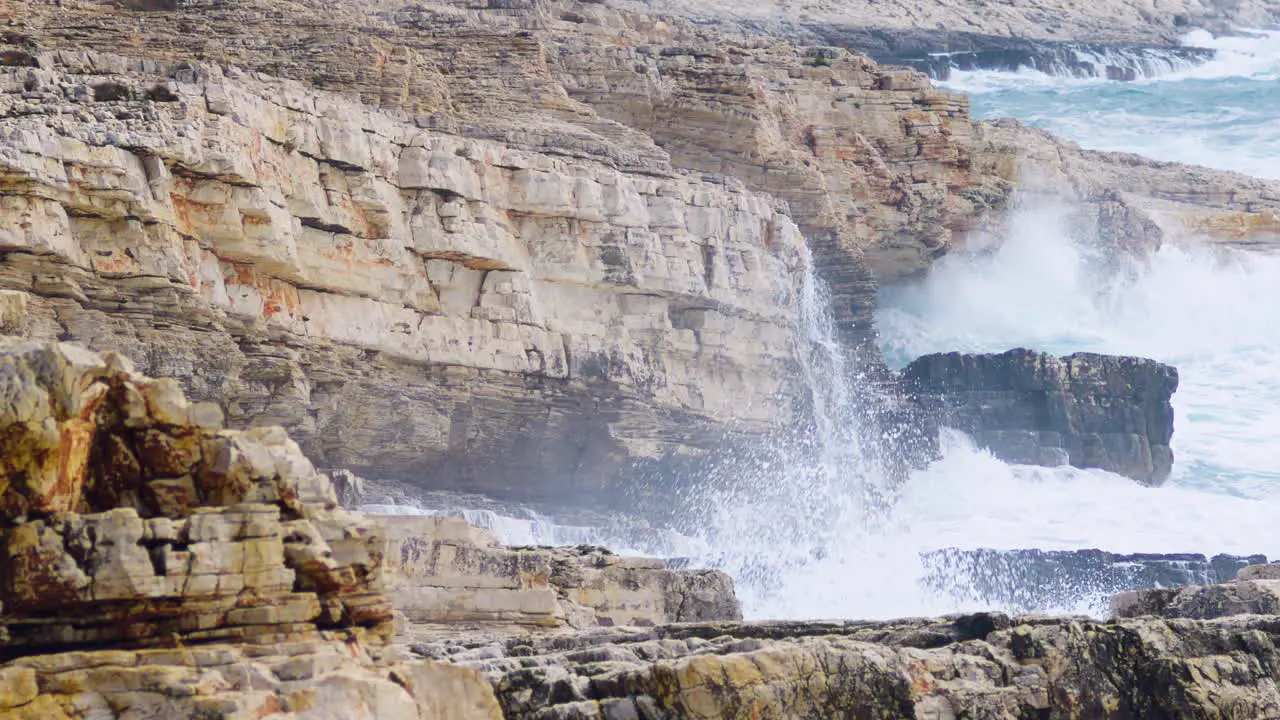 Big waves breaking on rocky shore creating mist and foam