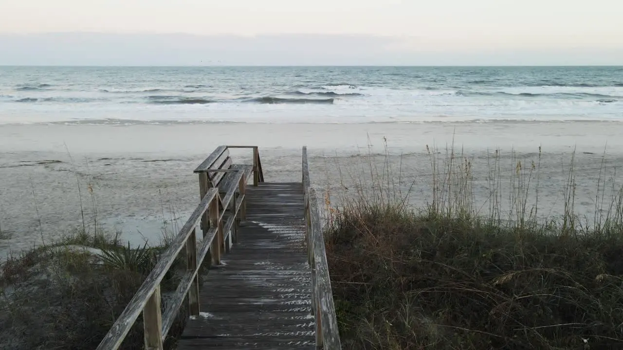 Still shot of beach walk with birds and waves in background at sunset