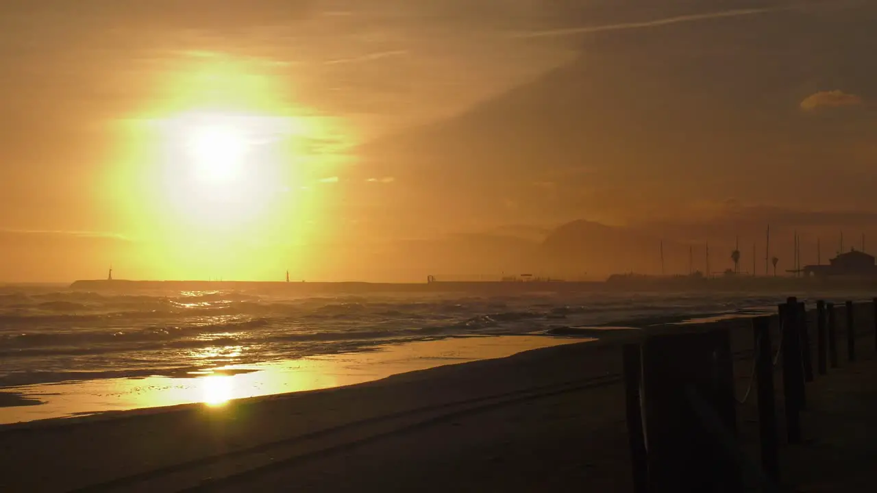 Hazy sunrise over sandy beach and harbor waves rolling in oliva mediterranean coast spain