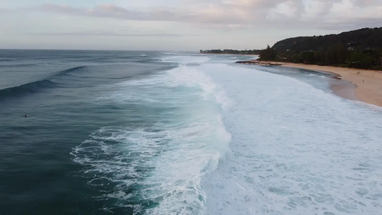 Cinematic drone shot of the famous waves crashing on the beach at Banzai Pipeline on Oahu's North Shore during sunset