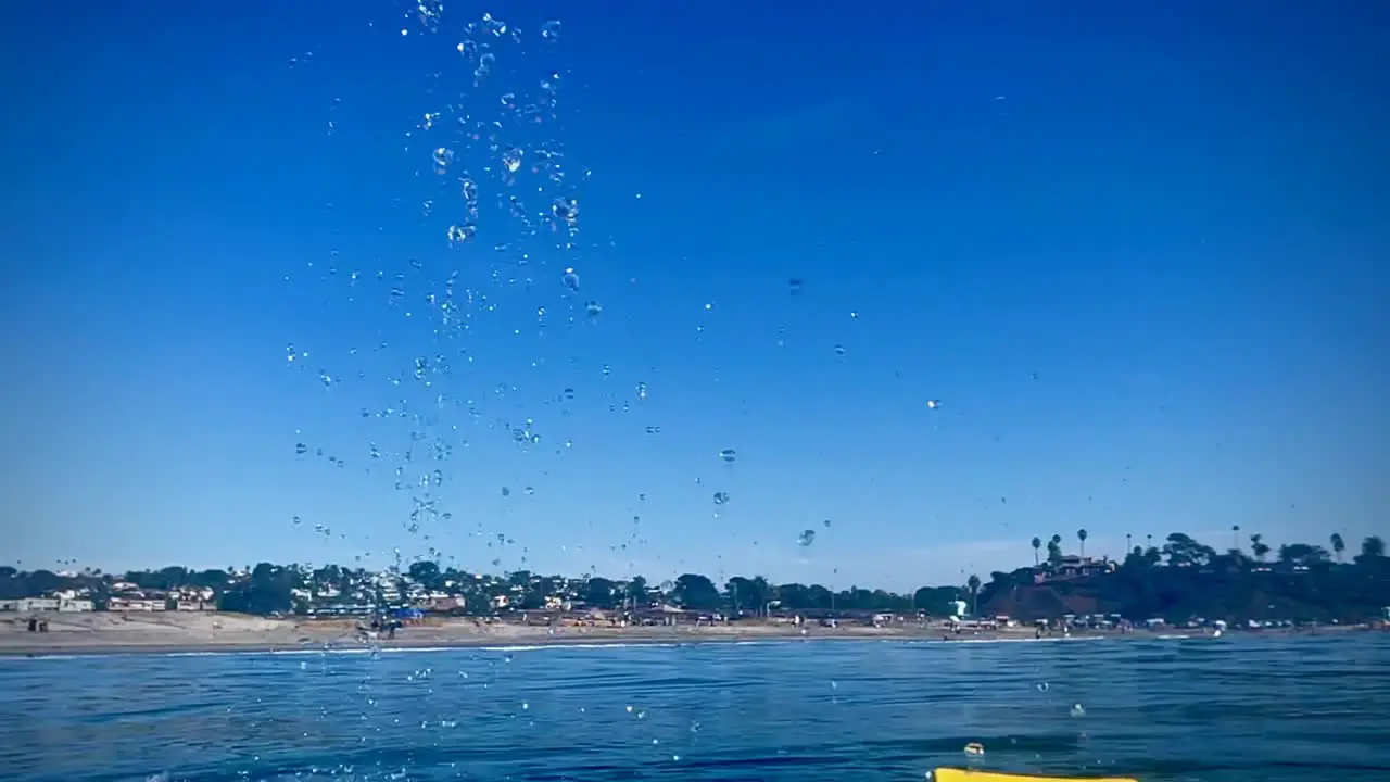 Swim fin throws water up and droplets fall in slow motion while swimming in Southern California