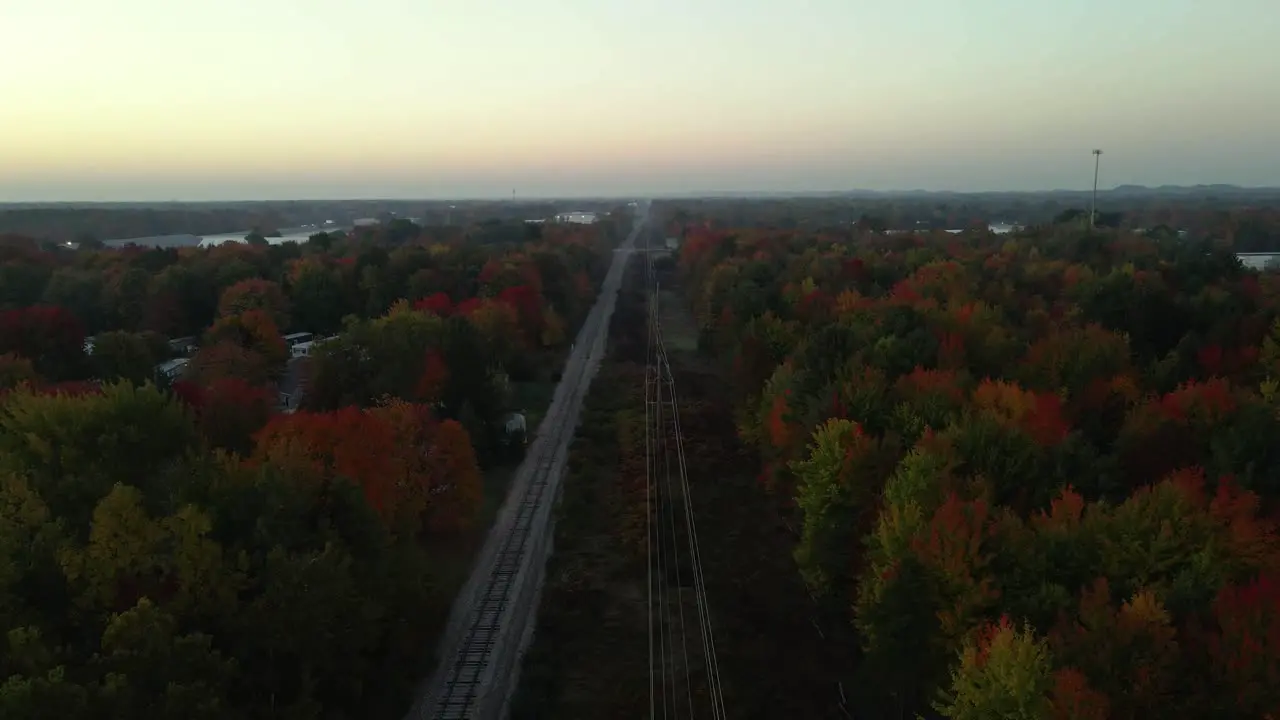 Forward track of a railroad section lined with trees blooming fall colors