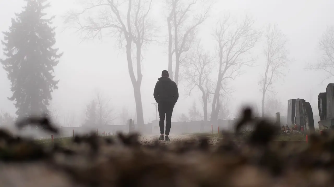 Slow Motion of Man Walking in Graveyard in Fog