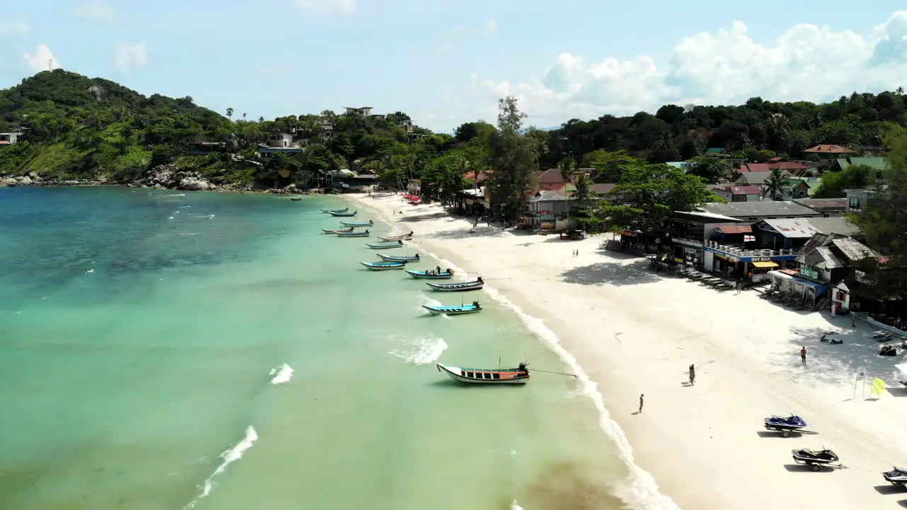 Backwards flight over a beach in Thailand with people and boats