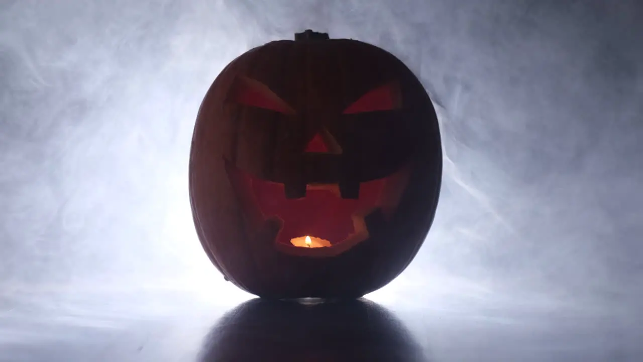 Halloween glowing pumpkin face in dark smoke fog