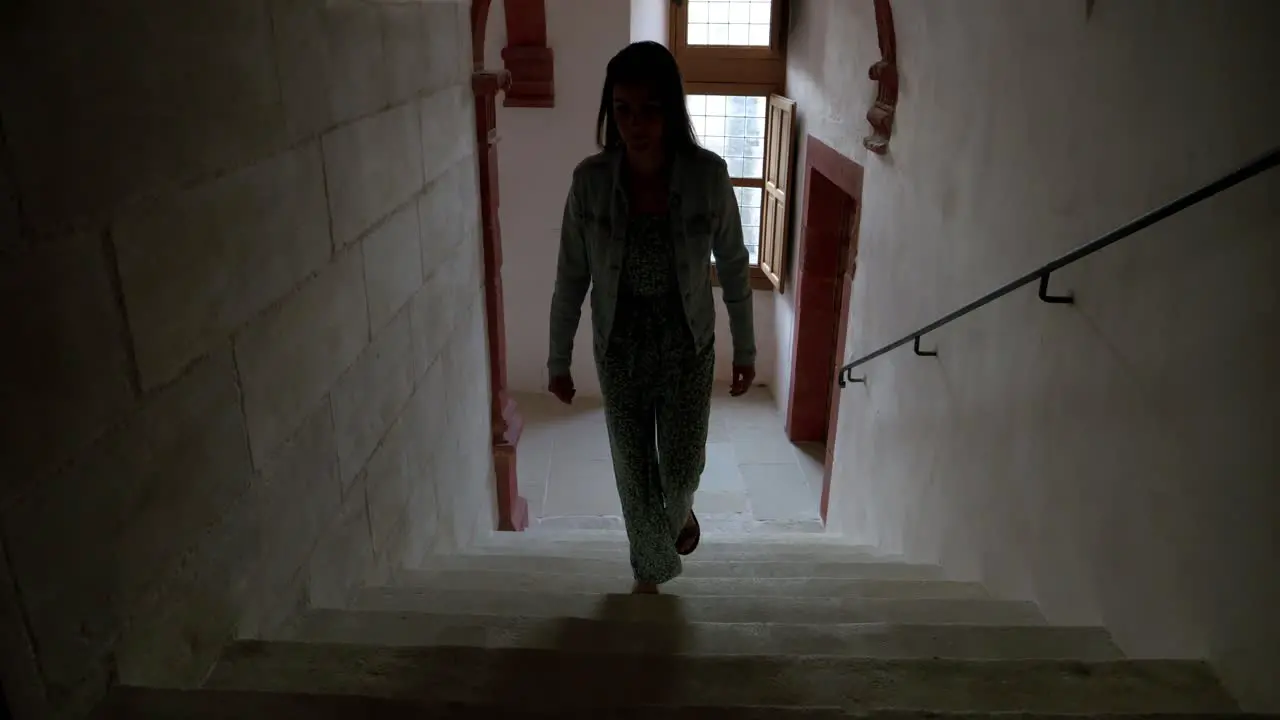 Woman walking up the stairs in a dark hallway