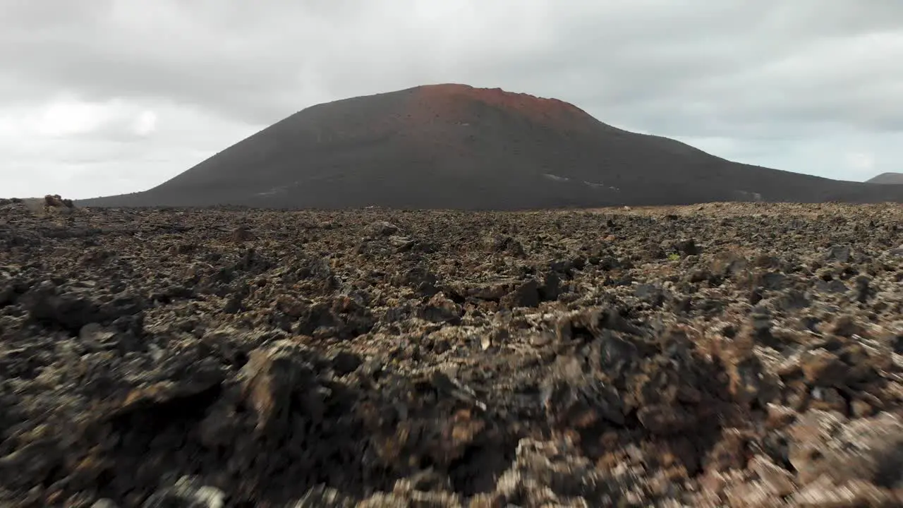 Flying low and fast towards a hill over volcanic rocks