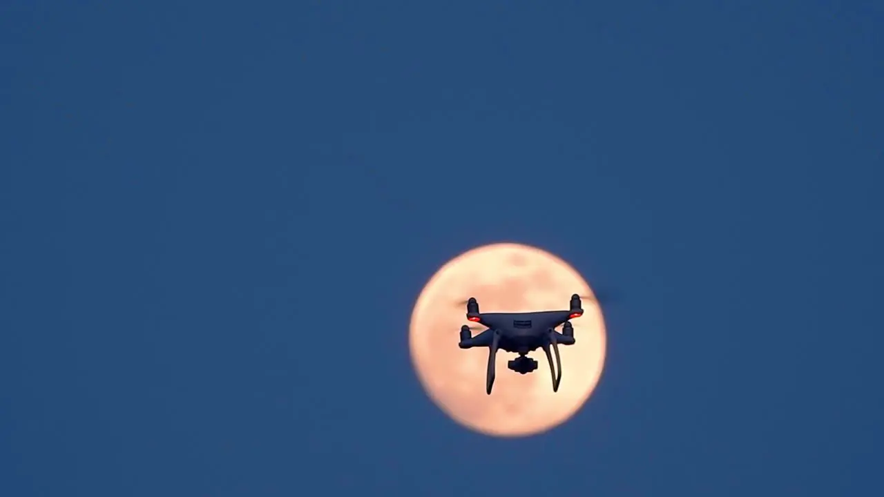 Drone flying in front of fullmoon in sunset