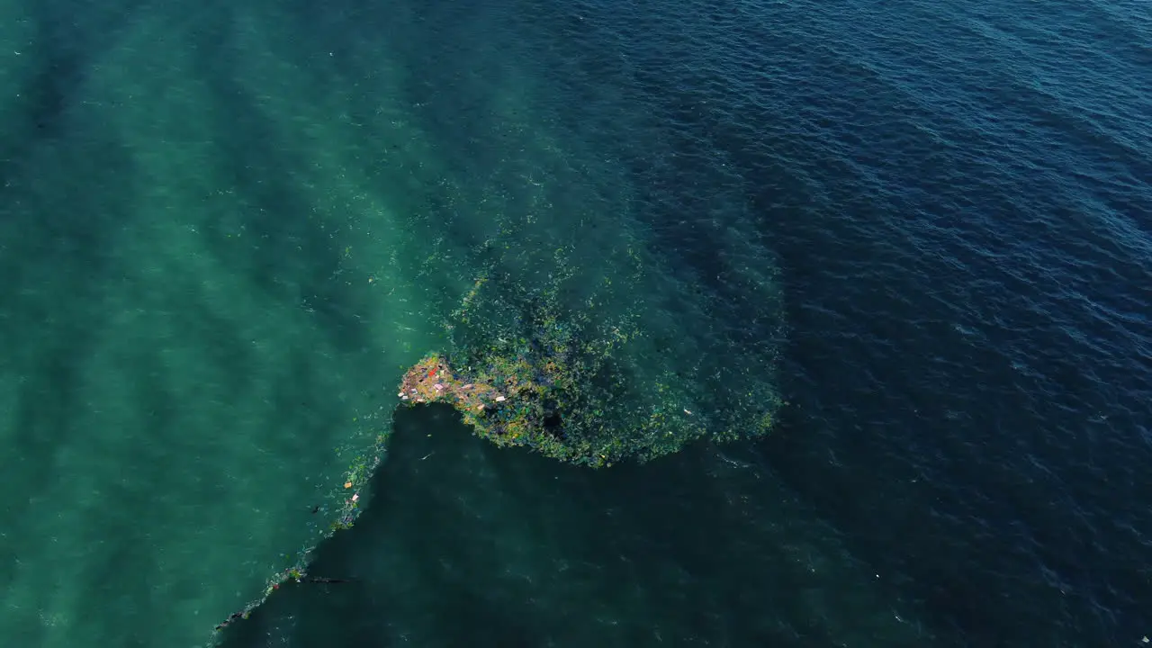 Aerial polluted plastic trash floating on ocean surface trapped in a current