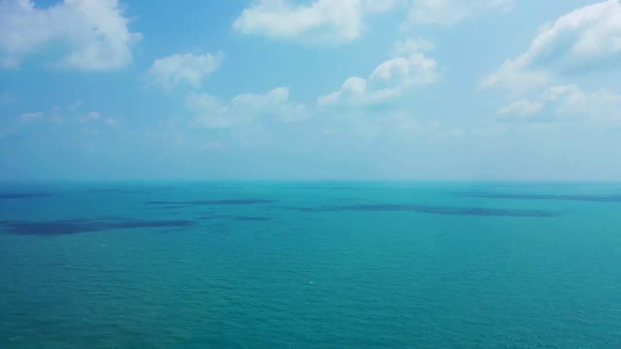 Ocean background bright blue sky with white clouds and tranquil water at open sea approaching horizon