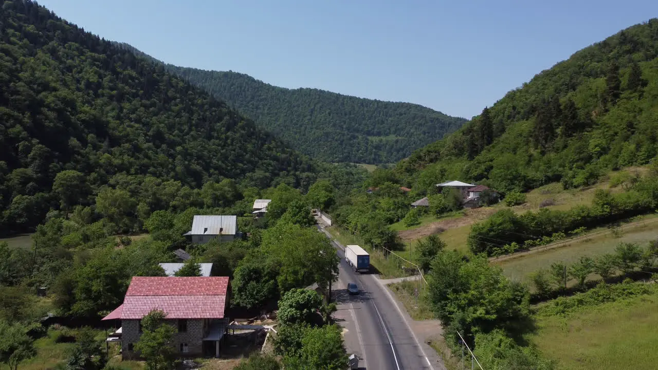 Drone following a large white truck through a valley on a Georgian road