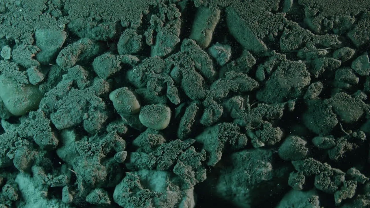 Moving dolly Close-up shot of layered green lit rocks and sand underground