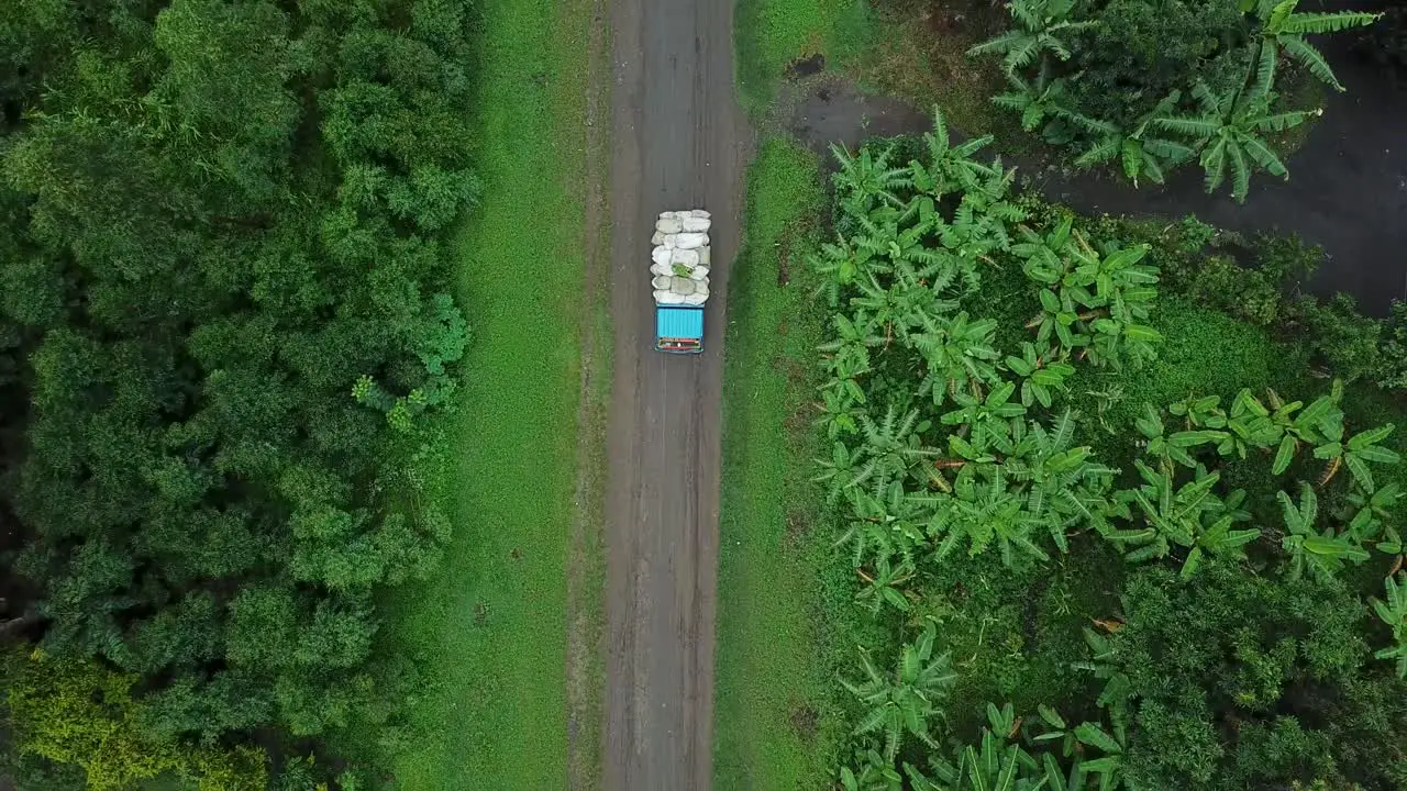 Aerial top down view of truck with bags of crop tropical surroundings