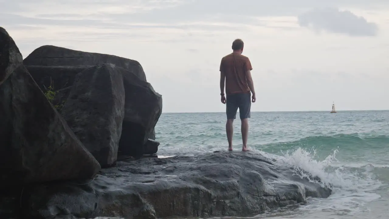 Rear Of A Man Standing On The Rock With Crashing Waves At Dam Trau Beach In Vietnam