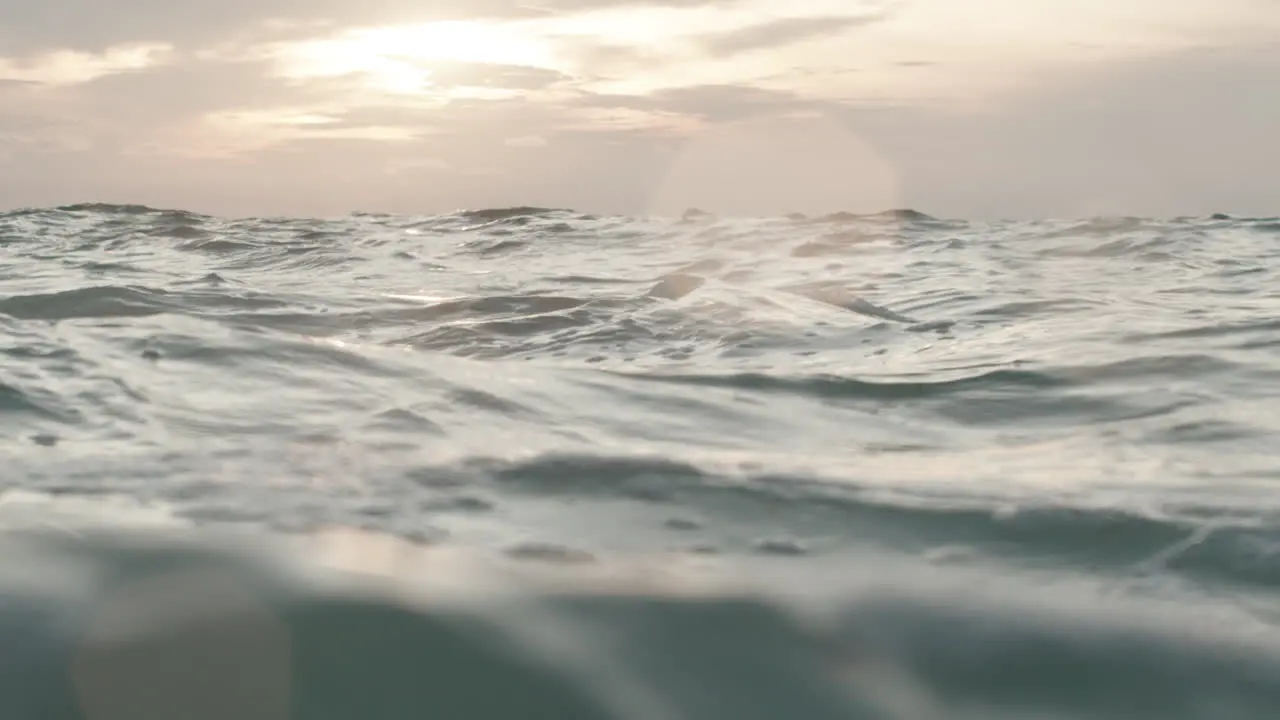 Low angle shot of big wavy sea surface with a sunset background in slow motion