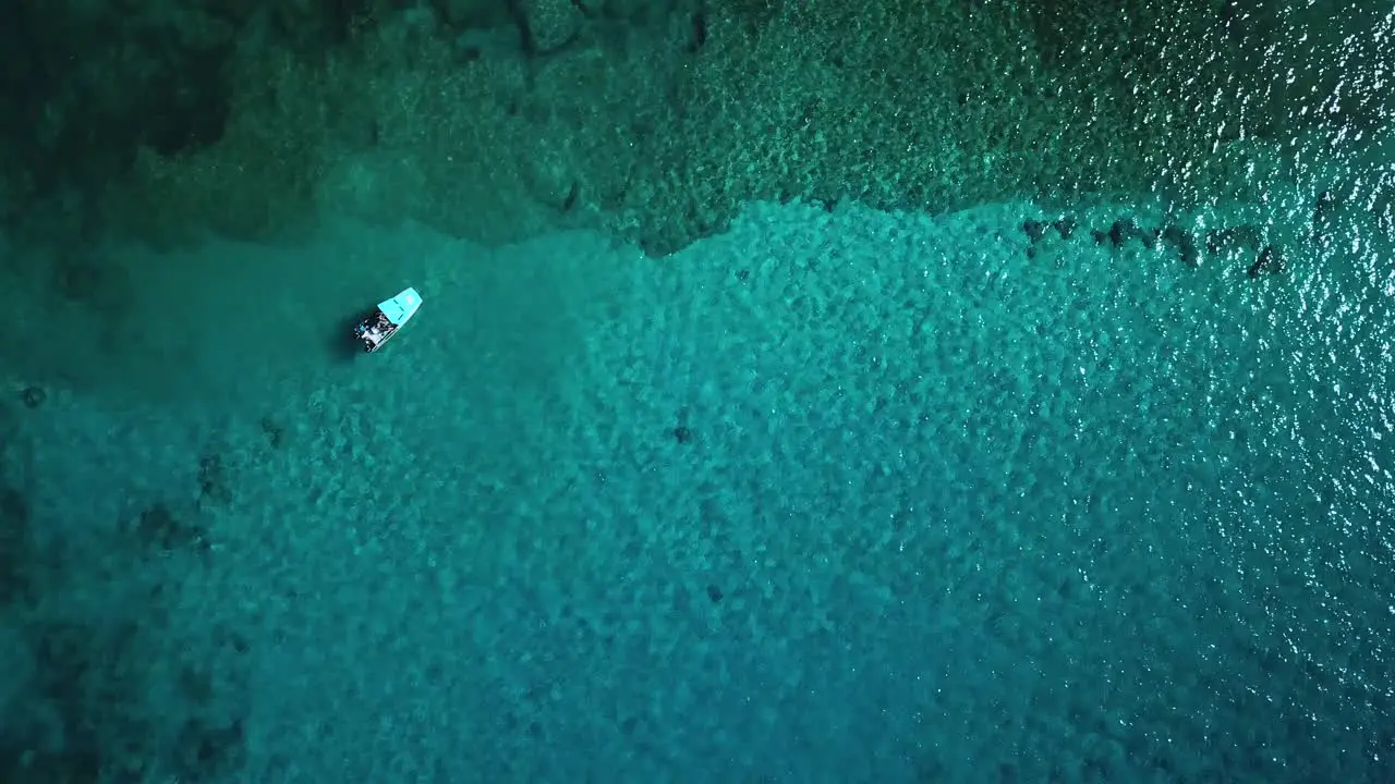 Aerial view above a boat anchored above a coral reef found in crystal clear water