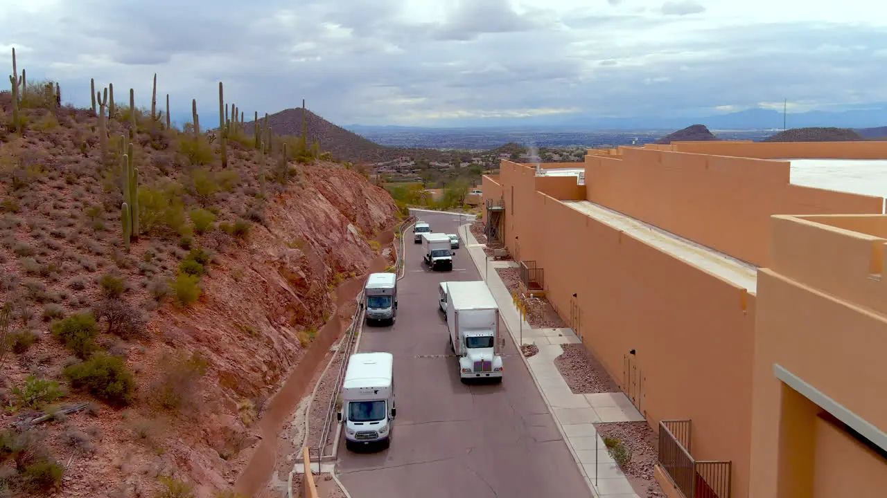 Drone shot of trucks pulling in behind a hotel or large building