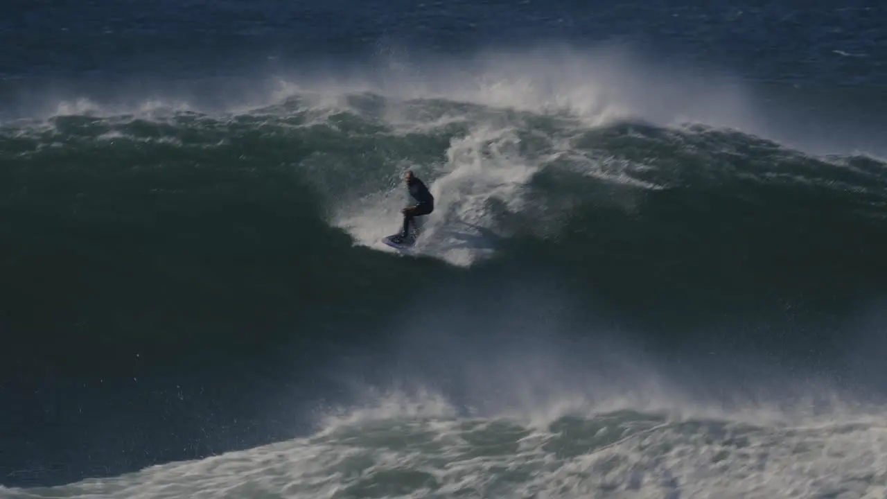 Surfer surfing huge waves of Nazare Portugal 360 trick or stunt extreme adrenaline dangerous sport in slow motion