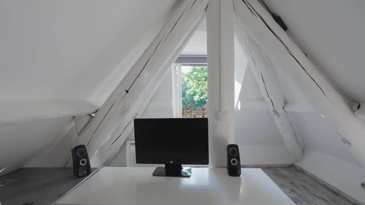 A white room located under the roof featuring a television and speakers