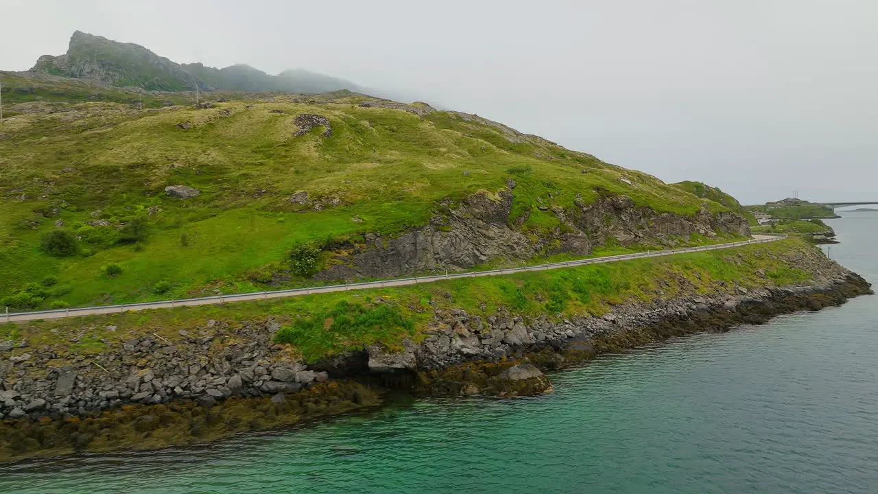 Cinematic aerial shot of a van driving along a scenic road on the Lofoten islands in Norway Europe Drone